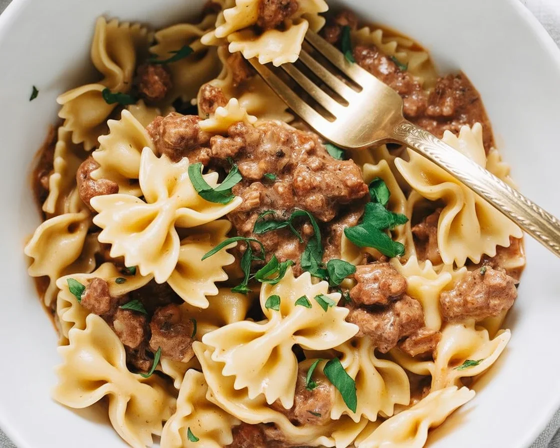 Creamy Beef and Bowtie Pasta topped with melted cheddar cheese in a rich sauce