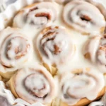 3-ingredient banana cinnamon rolls no yeast topped with icing on a plate.