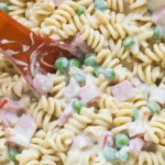 A vibrant bowl of Ruby Tuesday Pasta Salad with rotini, diced ham, peas, and creamy dressing.