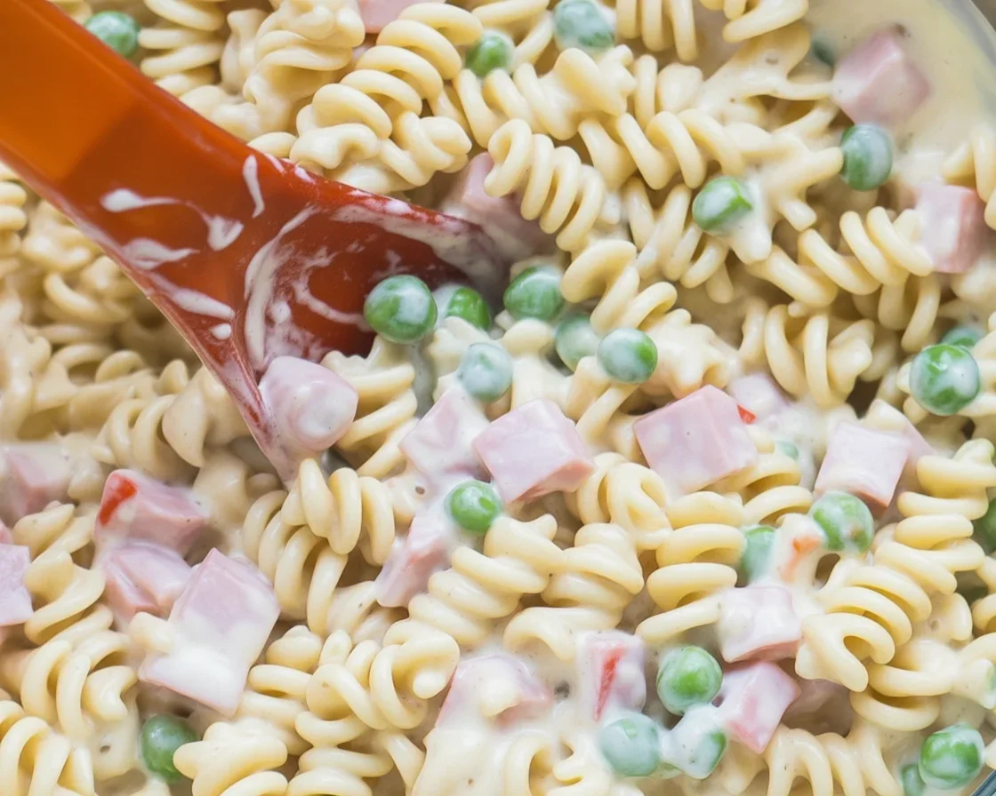A vibrant bowl of Ruby Tuesday Pasta Salad with rotini, diced ham, peas, and creamy dressing.