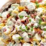 Delicious Loaded Potato Salad topped with bacon, cheddar cheese, and green onions.