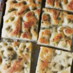 A freshly baked Garlic Parmesan Focaccia topped with olive oil and herbs.