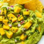 Fresh Guacamole with Mango Chunks served in a bowl, garnished with cilantro.