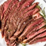 Sliced eye of round steak served with gravy and vegetables on a plate.