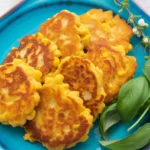 Plate of irresistibly crispy cheesy corn fritters garnished and ready to serve.
