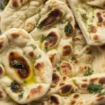 Buttery Garlic Naan Bread brushed with melted garlic herb butter served warm.