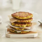 Delicious Potato and Carrot Fritters served with a side of dipping sauce.
