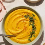 Creamy roasted carrot and parsnip soup served with crispy toppings.