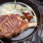 Delmonico Steak topped with aromatic Bay and Thyme Butter on a plate.