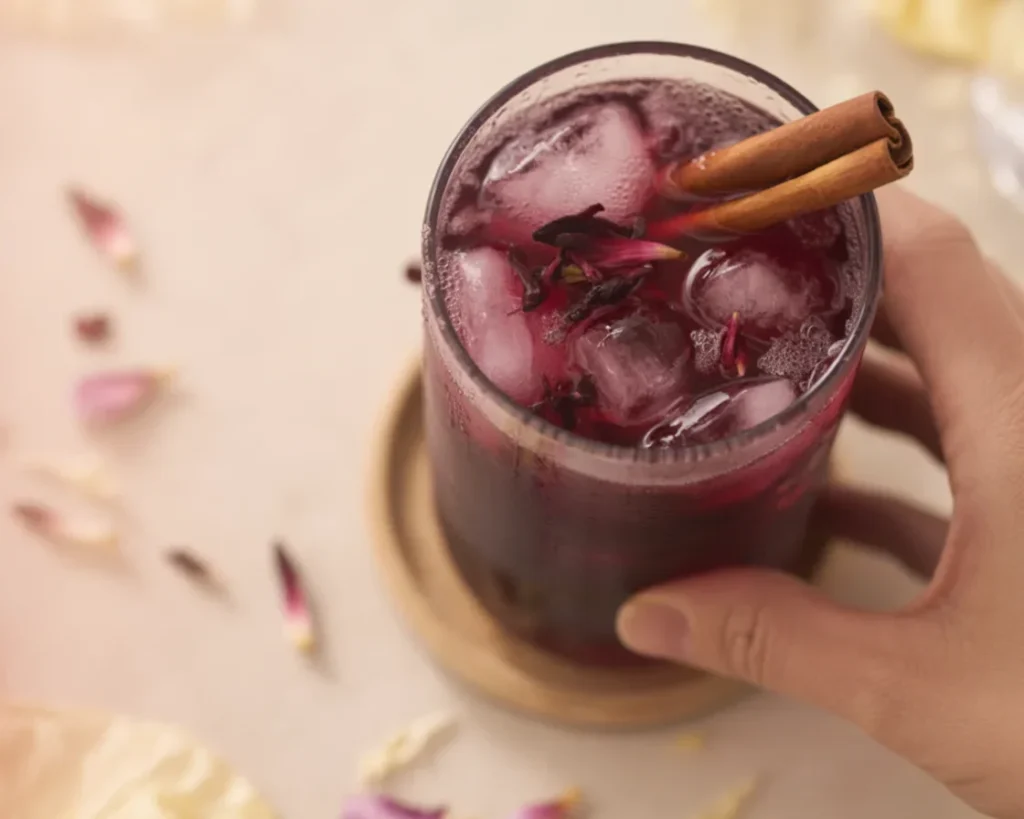 Spiced Hibiscus Agua Fresca served in a glass with cinnamon and hibiscus petals.