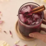 Spiced Hibiscus Agua Fresca served in a glass with cinnamon and hibiscus petals.